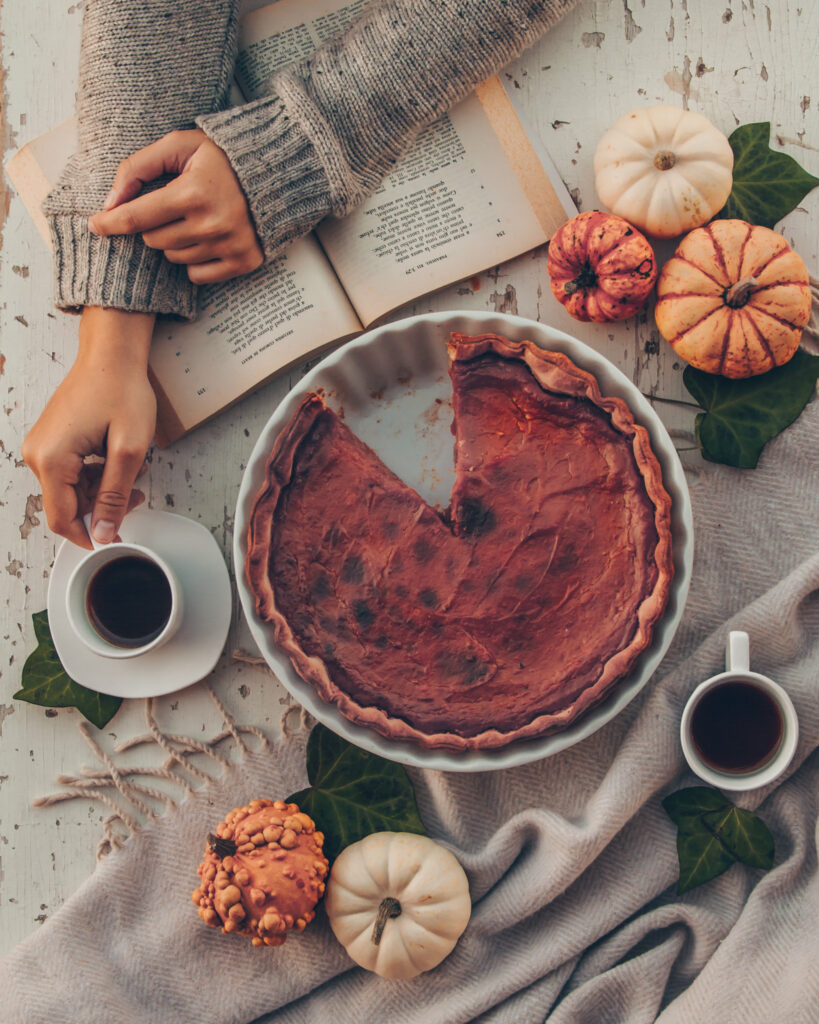 girl reading a book and drinking coffee with a pumpkin pie
